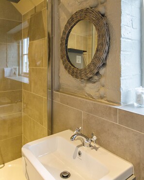A bathroom with a white sink, a mirror, and a stone wall.