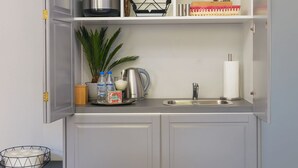Een compacte keuken met grijze kastjes, een roestvrijstalen spoelbak en een kroonluchter.