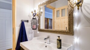 Een badkamer met een wit wastafelblad, een spiegel met een sierlijk omlijsting, en een handdoek aan een rek.