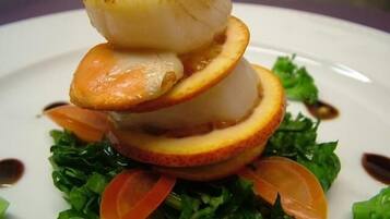 A plate with a layered food presentation including a grilled item, slices of fruit, and leafy greens.
