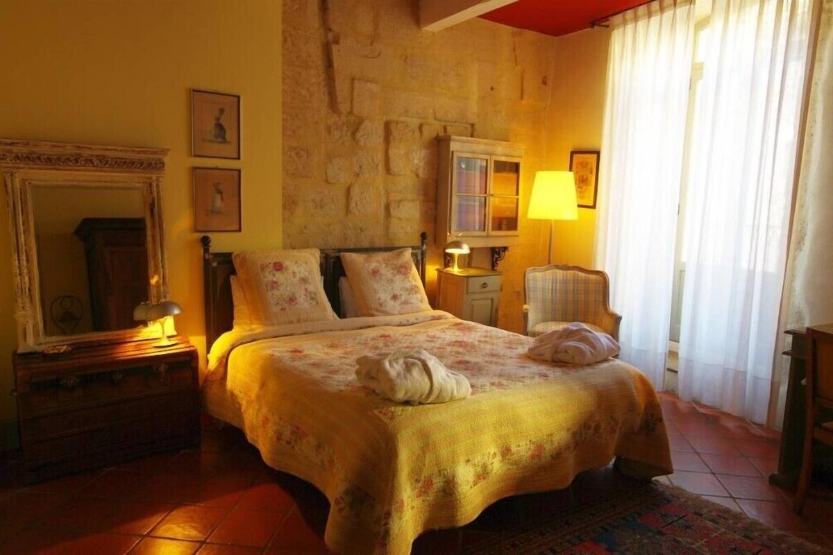 Um quarto aconchegante com uma cama, cômoda, espelho e abajur.
