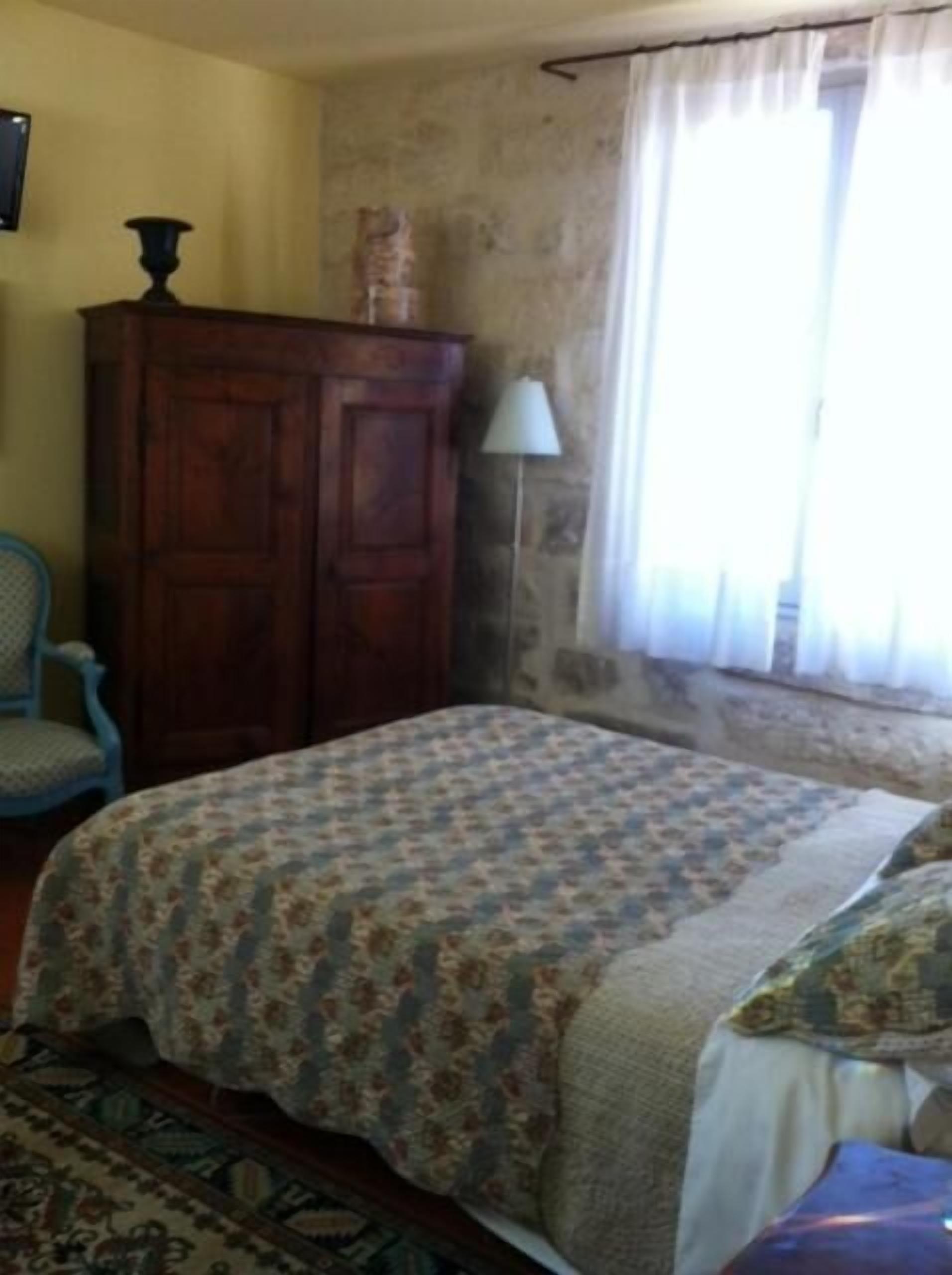 Une pièce comprenant un lit, une armoire en bois, une chaise et une lampe.
