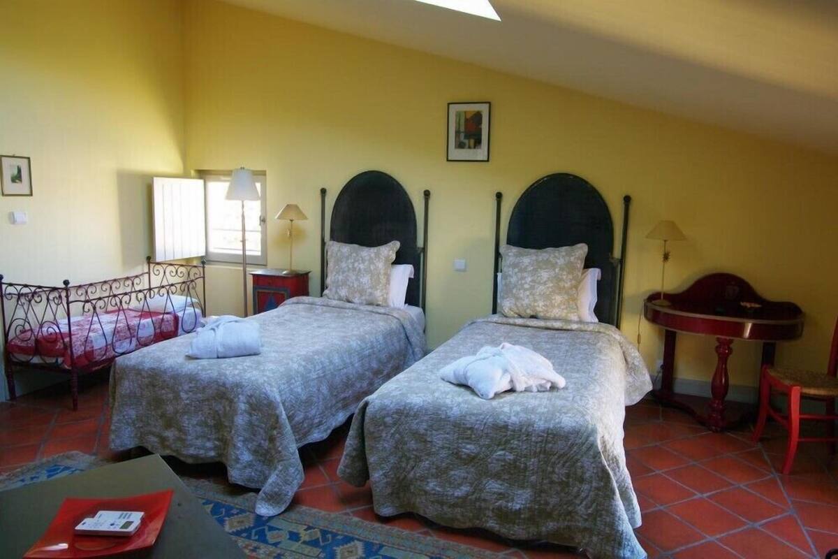 Quarto com duas camas, uma mesinha e uma cadeira.