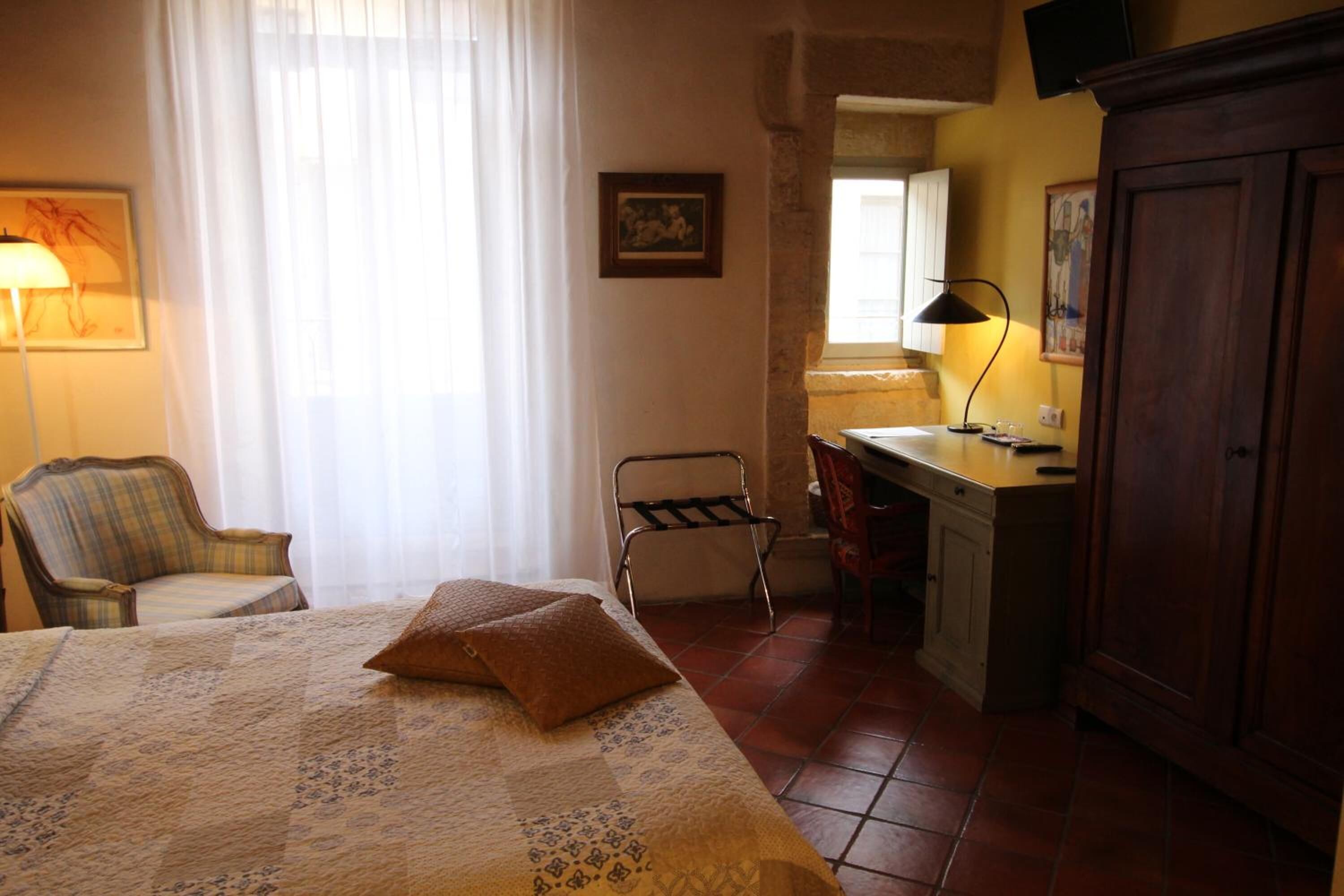 A bedroom with a bed, a desk, a chair, and a wardrobe.