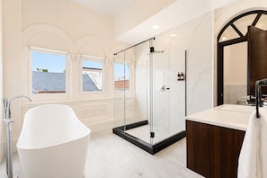 A modern bathroom with a freestanding bathtub, a glass-enclosed shower, and a vanity with a mirror. - Magnolia Inn (Panama City)