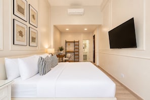 A hotel room with a bed, a desk, a chair, a TV, and framed pictures on the wall. - Magnolia Inn (Panama City)