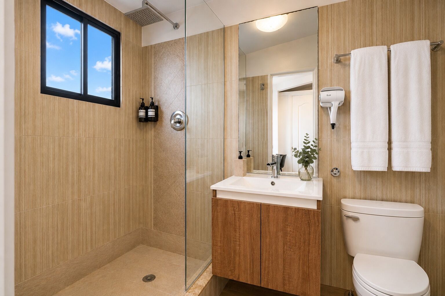 Une salle de bain moderne avec une douche à parois de verre, un lavabo blanc avec un miroir et des toilettes.