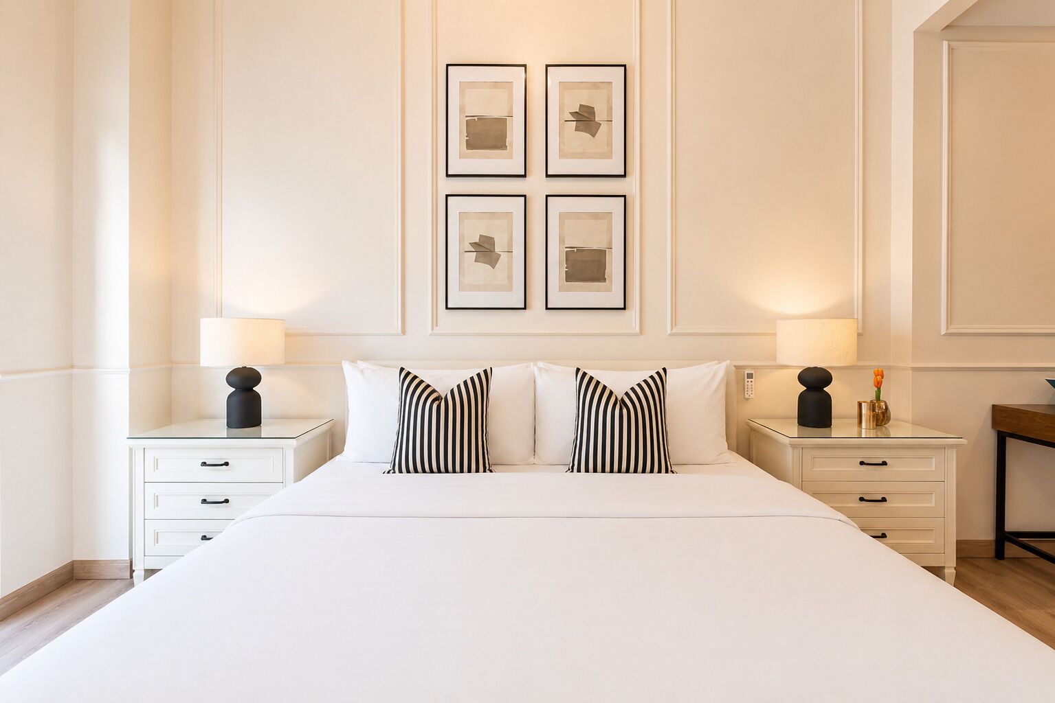 A hotel room with a large bed, two bedside tables, and wall-mounted artwork.