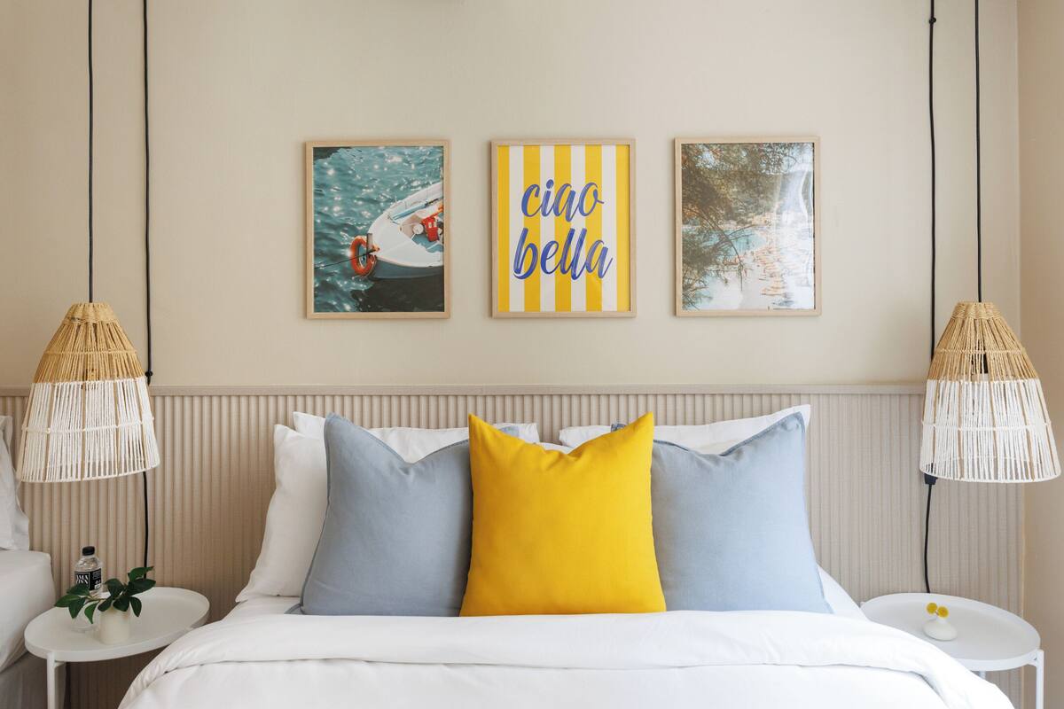 A neatly arranged hotel room with a bed, two bedside tables, and three framed pictures on the wall.