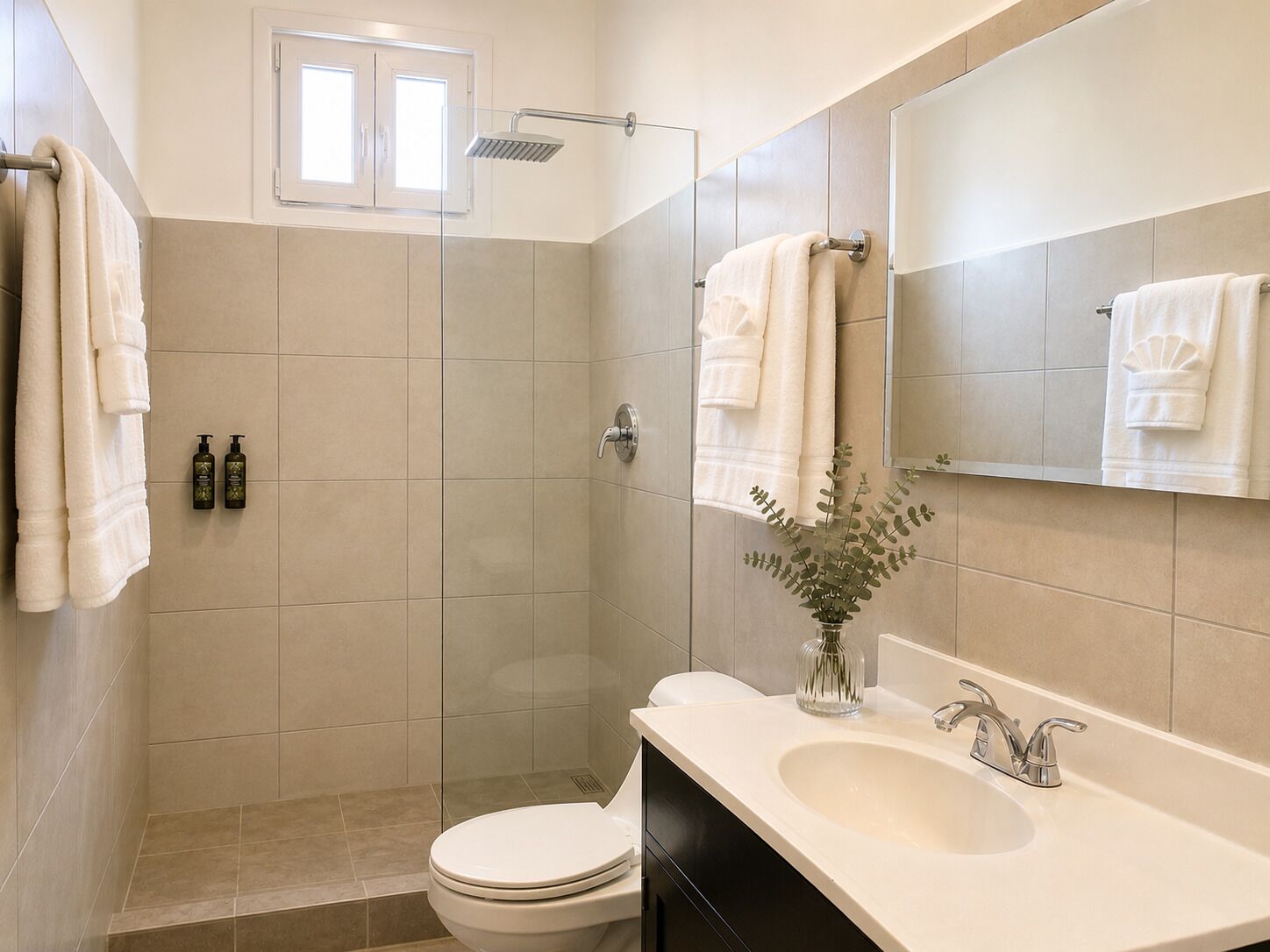 Un baño con inodoro, lavabo, espejo, ducha y toallas.