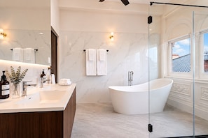 A modern bathroom with a freestanding bathtub, a vanity with a mirror, and a glass shower enclosure. - Magnolia Inn (Panama City)