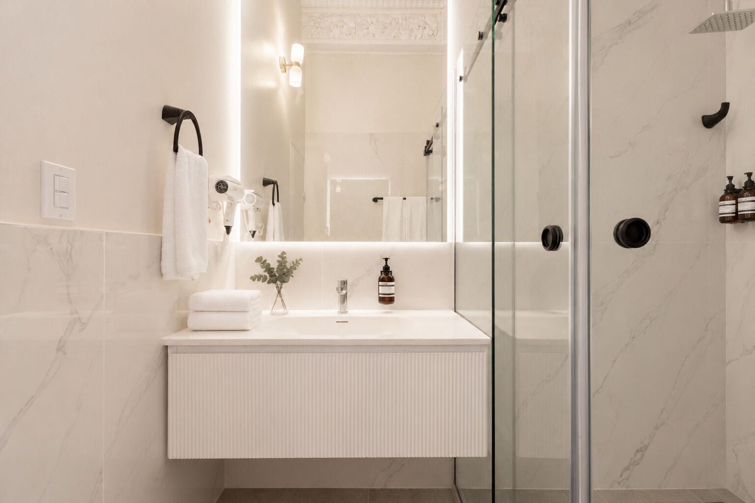 A modern bathroom with a glass shower enclosure, a white vanity, and a mirror.