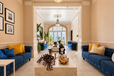 A spacious living room with blue sofas, a marble coffee table, and framed pictures on the walls.. Magnolia Inn