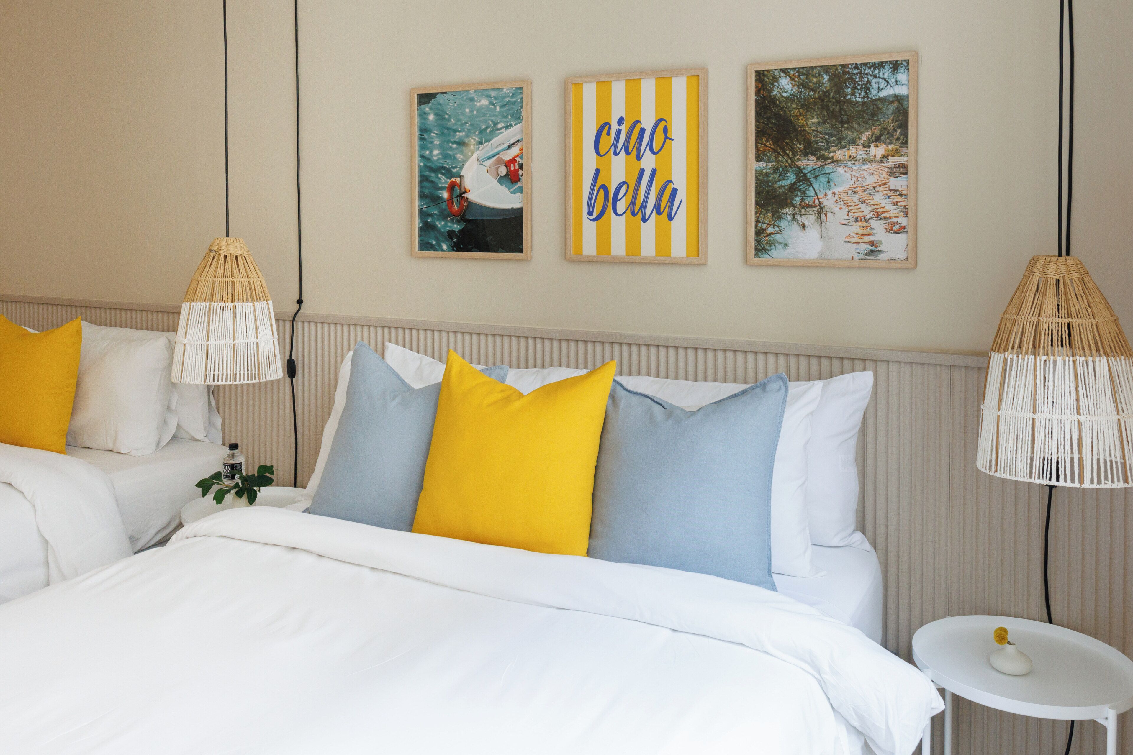 A hotel room with a bed, two bedside tables, and wall art.