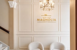 A hotel interior with a chandelier, a sign reading 'Hotel Casa Magnolia Inn,' and two chairs. - Magnolia Inn (Panama City)