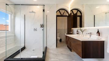 A modern bathroom with a glass-enclosed shower, a wooden vanity, and a marble floor.