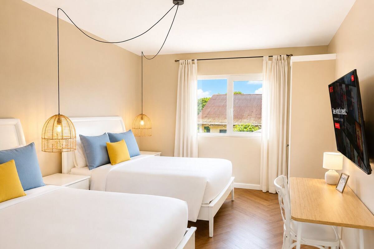 A hotel room with two beds, a desk, a chair, a TV, and a window with curtains.