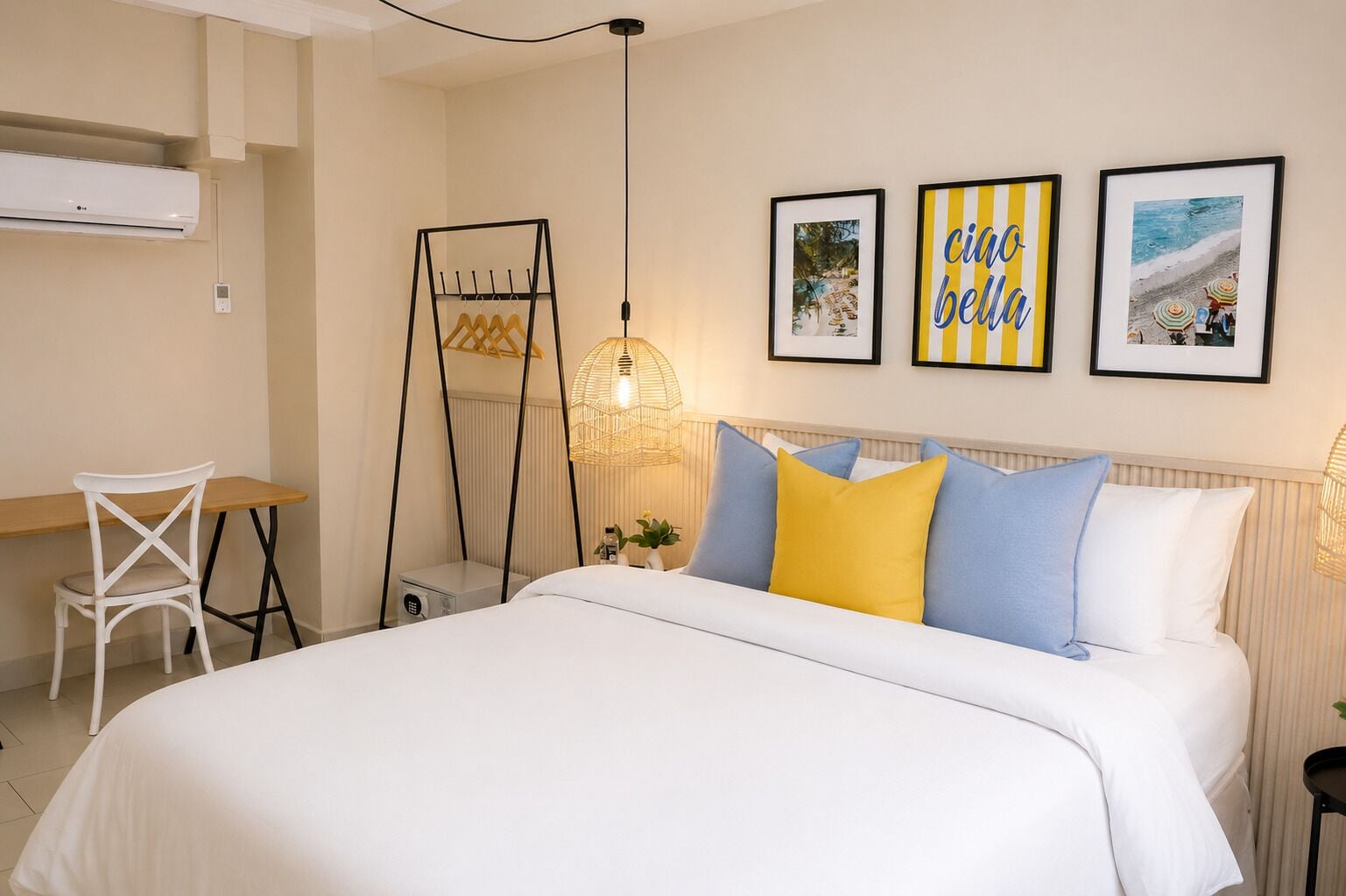 A bedroom with a bed, a desk, a chair, and three framed pictures on the wall.