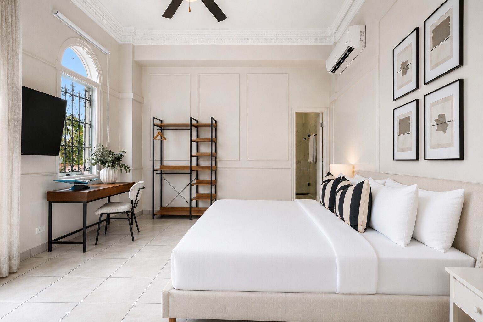 A hotel room with a bed, desk, chair, and a wardrobe.
