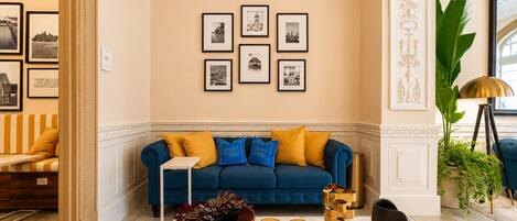 Ein Wohnzimmer mit einem blauen Sofa, gelben Kissen, einem Couchtisch und gerahmten Bildern an der Wand.