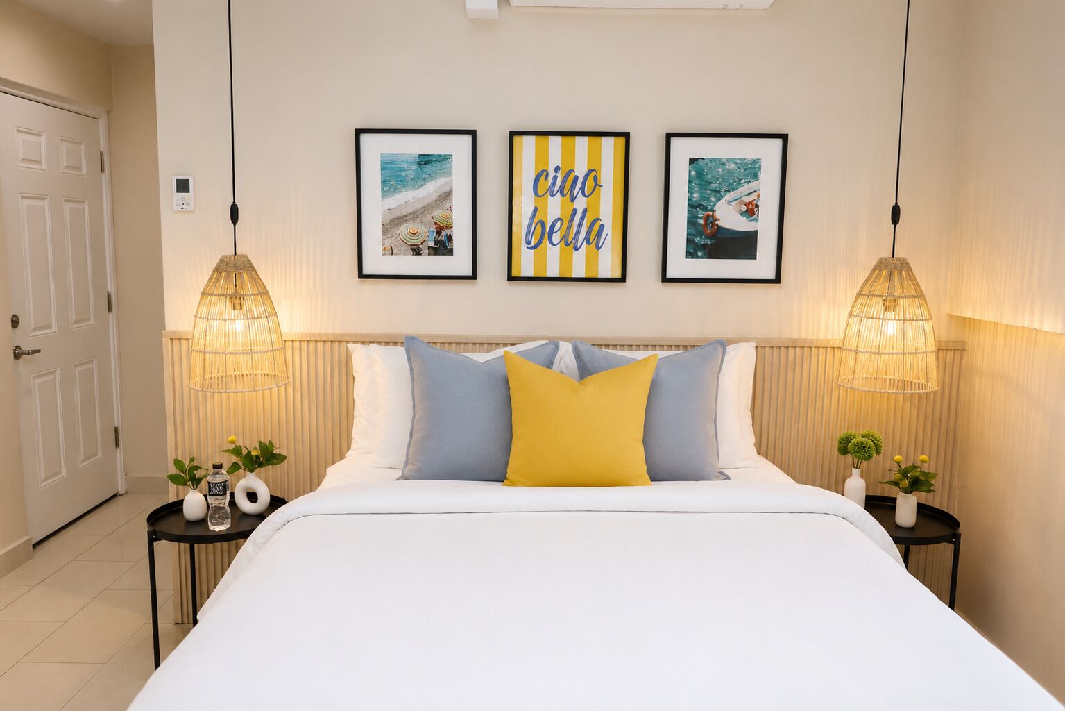 A hotel room with a bed, two bedside tables, a wall-mounted light fixture, and three framed pictures.