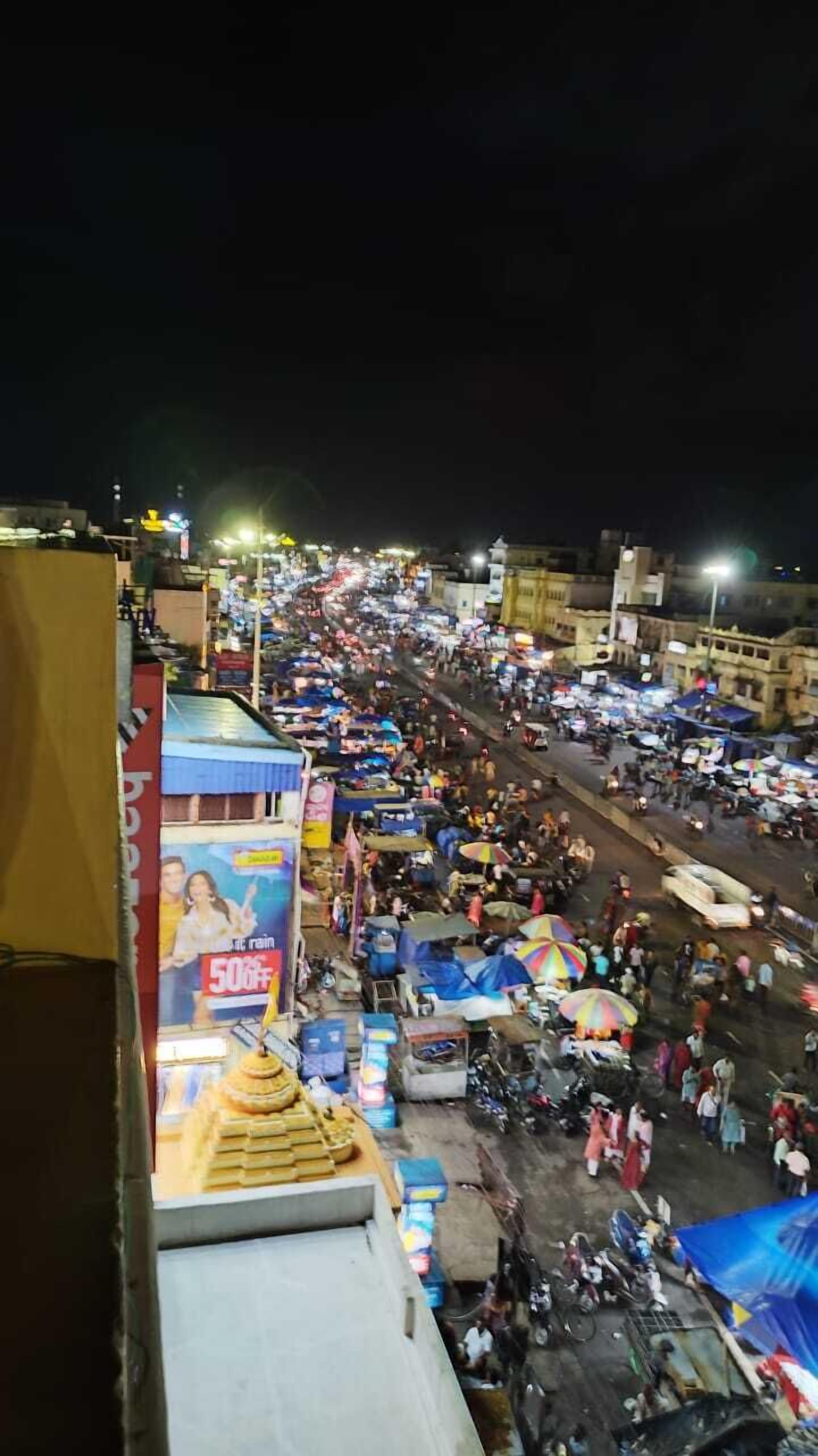 A crowded street market at night with various stalls and people.