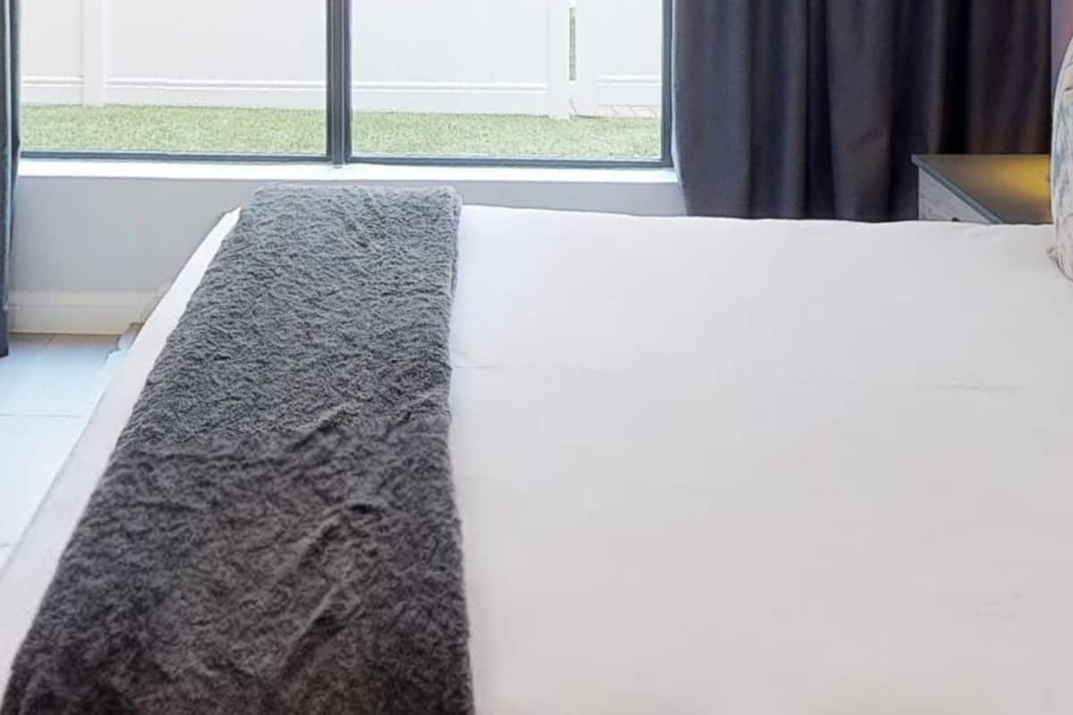 Een hotelkamer met een bed, een raam met gordijnen en uitzicht op buiten.