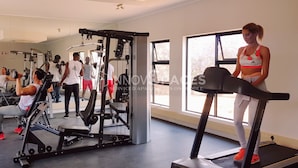 Une salle de sport équipée de matériel d’exercice, d’un tapis de course et d’un grand miroir.