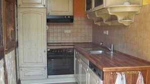 Une cuisine avec des meubles de rangement en bois, une cuisinière et un évier.