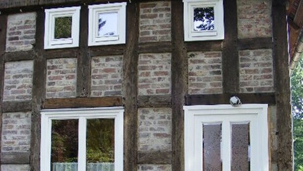 Un bâtiment traditionnel à colombages, avec une porte et des fenêtres peintes en blanc.