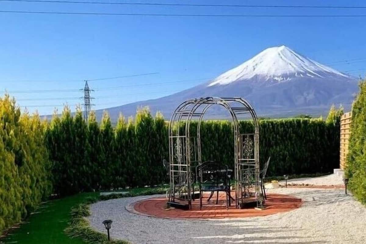 Ein Garten mit einem Metall-Gazebo, einem Kiesweg und einer Hecke.
