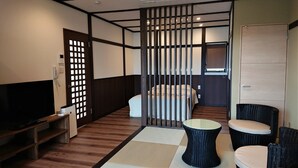 Een kleine hotelkamer met een bed, een televisie, een tafeltje en twee stoelen.