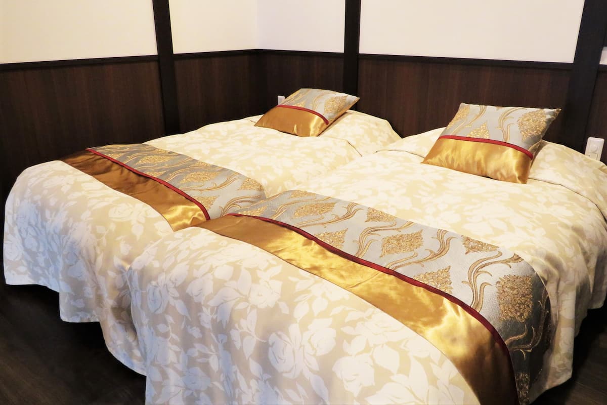 Ein Doppelbett mit einem blumigen Bettüberwurf und zwei Kissen, ein Holzkopfstück und ein dunkler Holzboden.