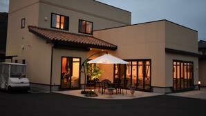 Een modern gebouw met een patio, buitenmeubilair en een parasol.