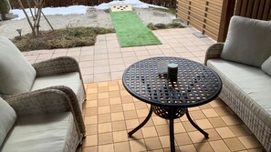 Een terras met rieten meubels en een ronde tafel met een onderzetter.