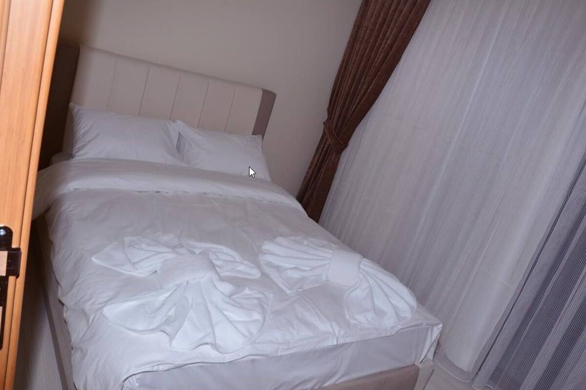 Un lit simple avec une tête de lit blanche et un couvre-lit blanc.