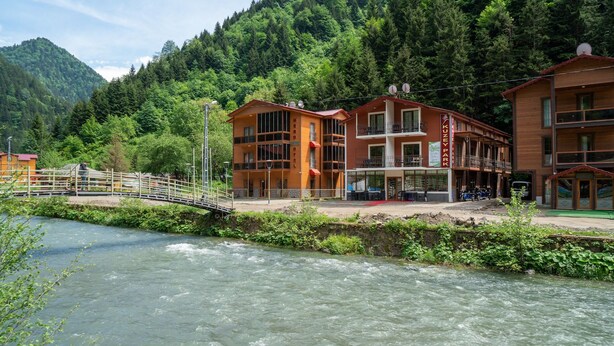 Un hotel de diseño moderno cerca de un río con un puente de madera.