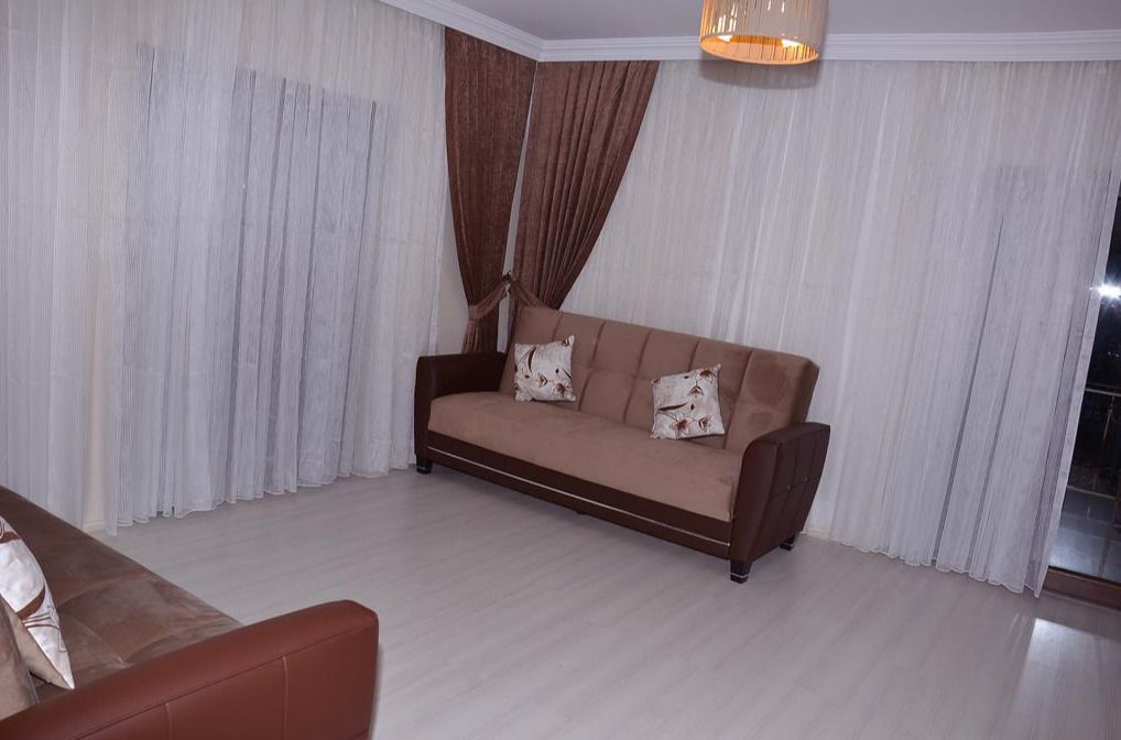 A living room with a sofa, curtains, and a hanging light fixture.