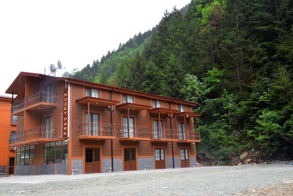 A multi-story hotel with balconies, located near a forested area.