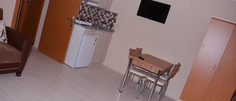 A compact living space with a kitchenette, a dining area, and a wardrobe.