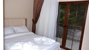 Un dormitorio con una cama grande, una ventana con vistas a zonas verdes y una puerta corrediza de vidrio.