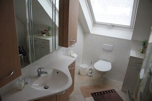 Un baño moderno con tragaluz, lavamanos, inodoro y zona de ducha.