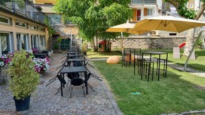 Un espace extérieur aménagé avec des tables et des chaises, un grand parasol et une plante en pot.