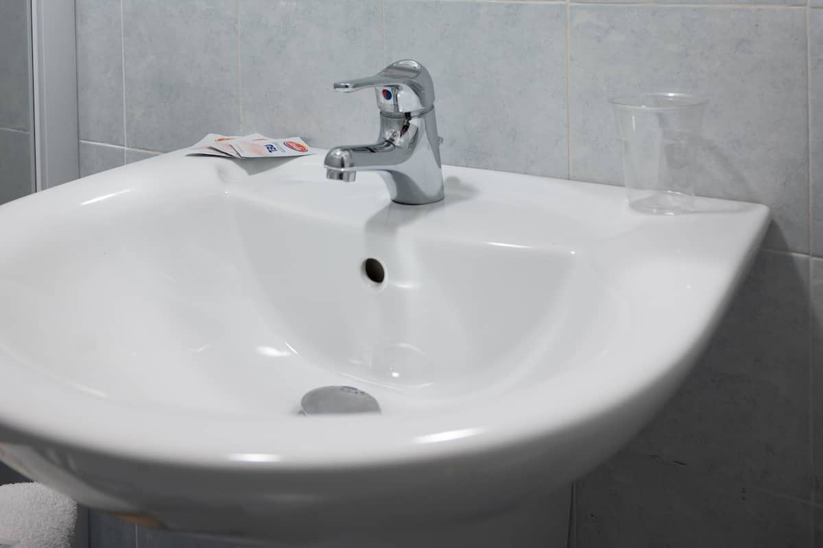 Ein Badezimmer mit einem weißen Waschbecken, einem Spiegel und einer Duschkabine aus Glas.