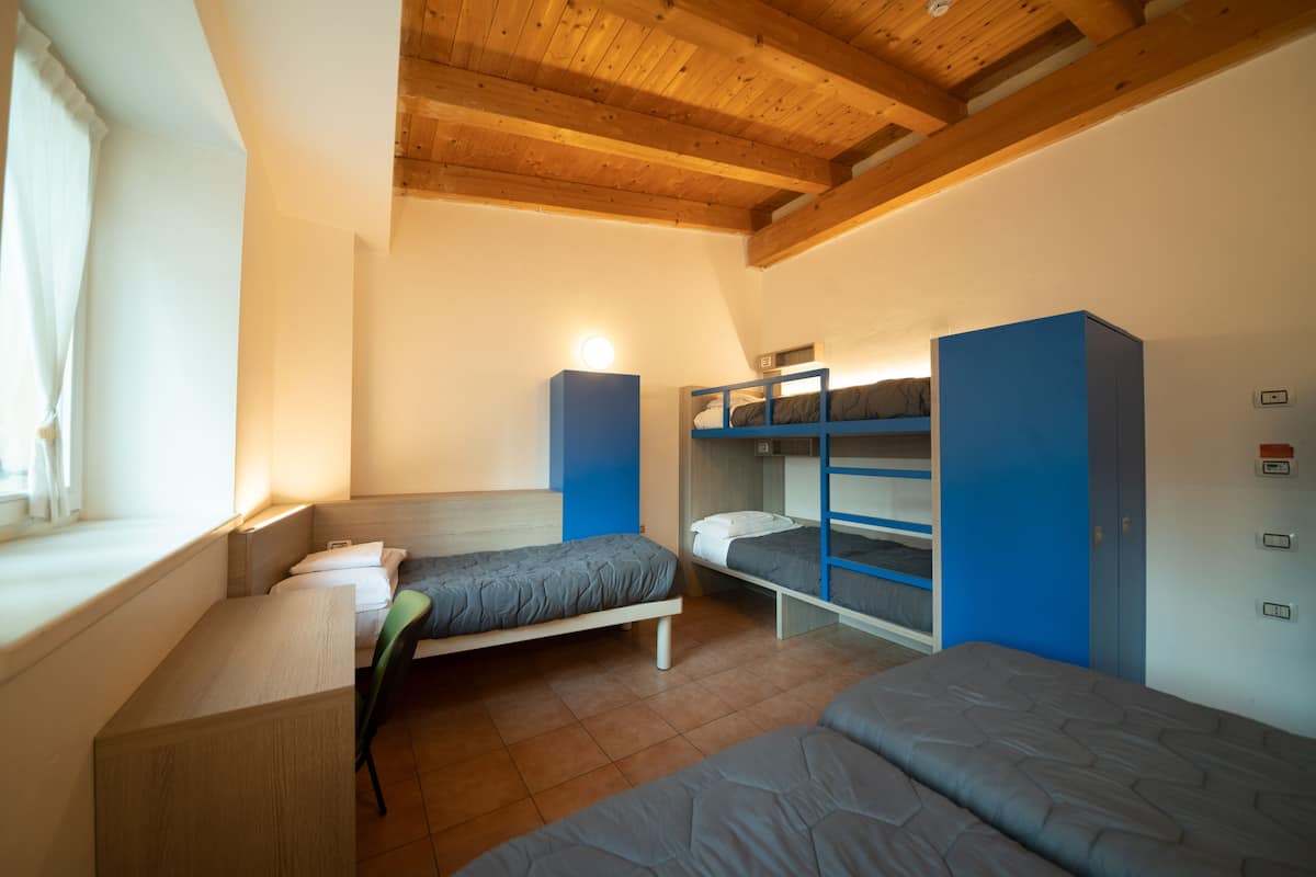 Ein Schlafsaalzimmer mit Stockbetten, einem Schreibtisch und einem Fenster.