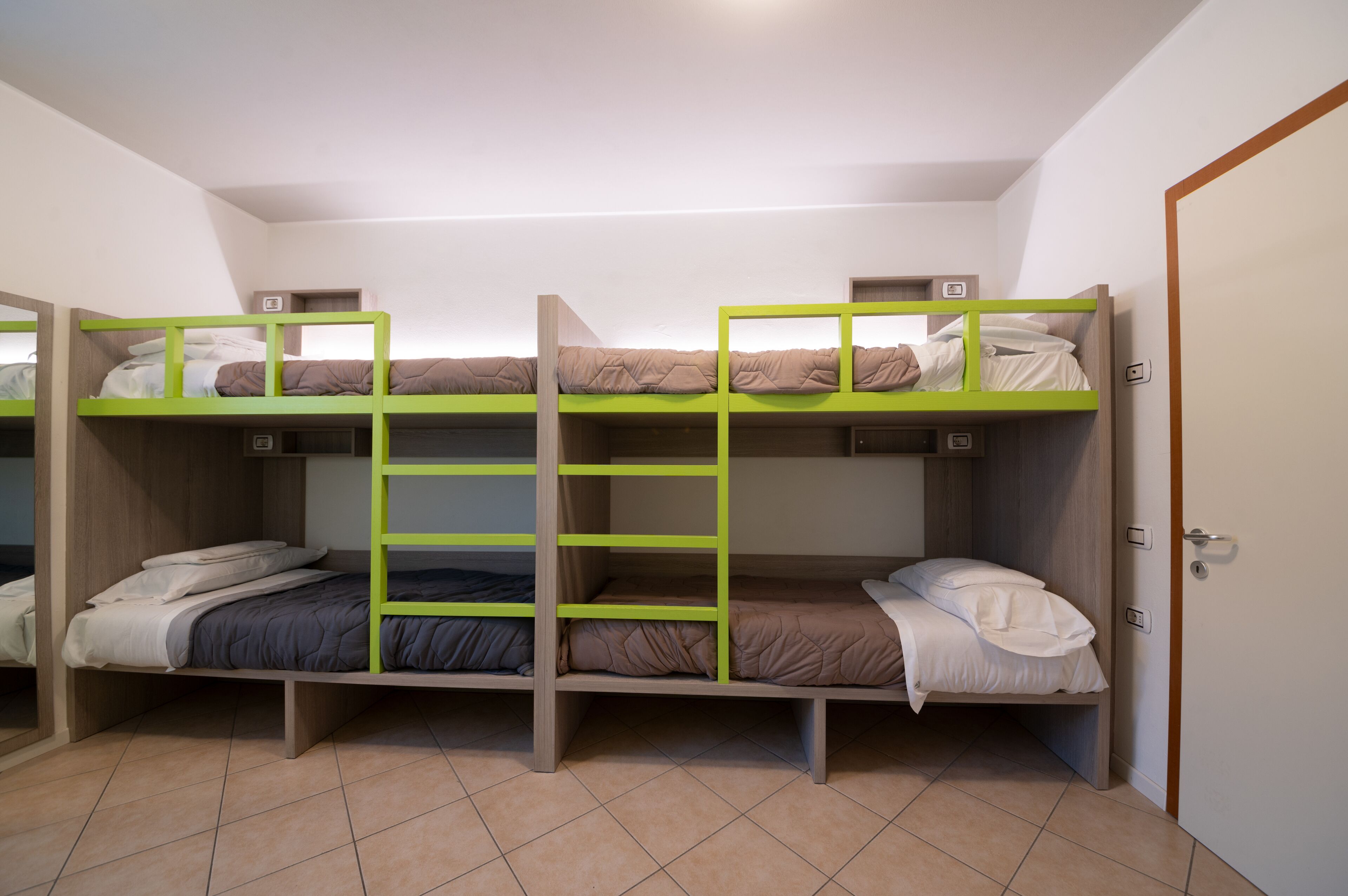 A room with bunk beds, a door, and a tiled floor.