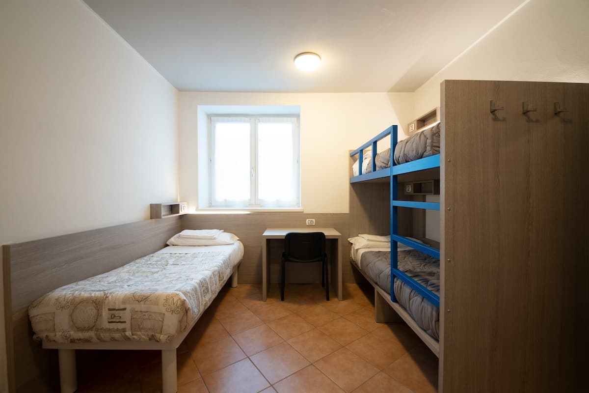 Ein Schlafraum mit zwei Einzelbetten, einem Schreibtisch und einem Stuhl.