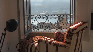 A room with a view of a cityscape through a window with a decorative iron railing. - Mo House (Porto)