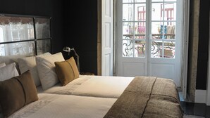 A bedroom with two beds, a large window, and a view of the street outside. - Mo House (Porto)