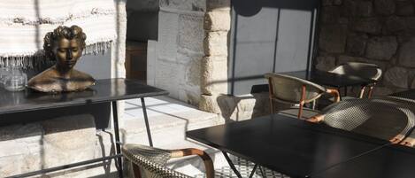 A dining area with stone walls, wicker chairs, and a black table.